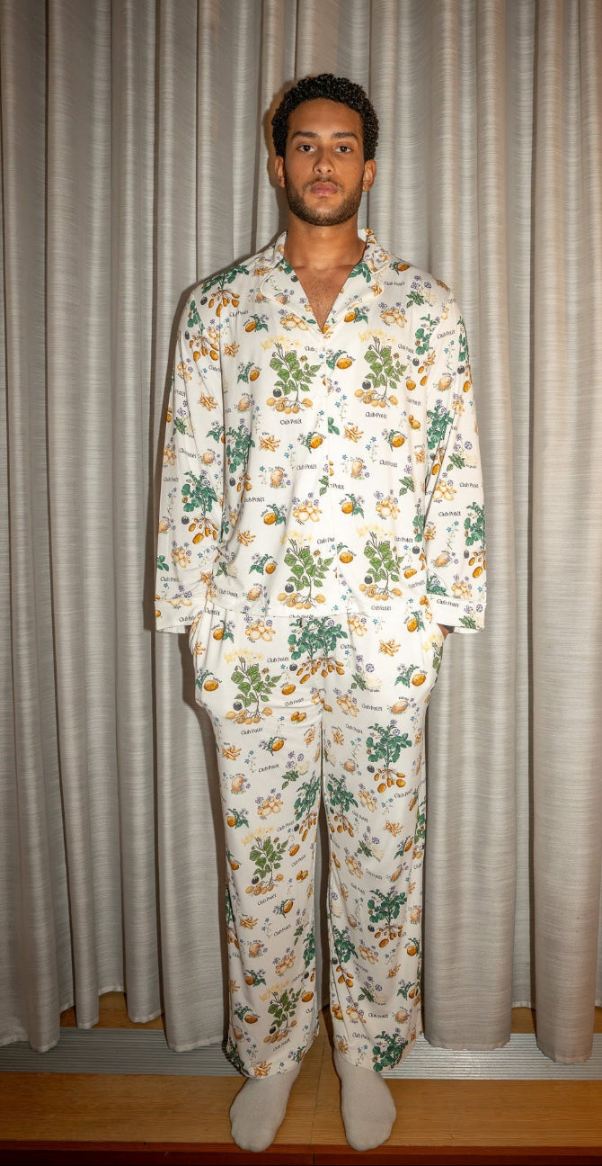 Michols Pena wearing a potato floral pajama set standing against a neutral curtain background